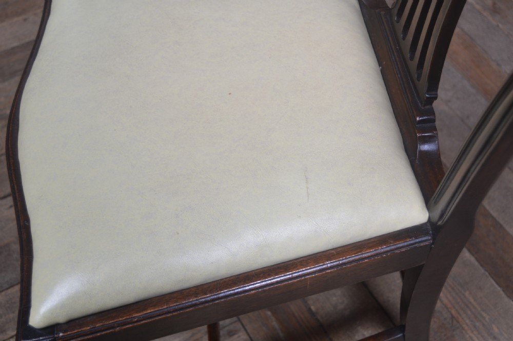 A set of eight dark mahogany Edwardian dining chairs with carved rosette back splats and cream upholstered seats, including two carvers. View VI