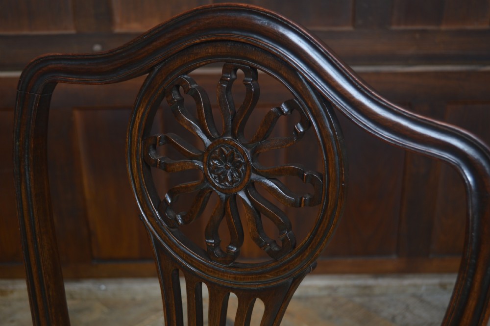 A set of eight dark mahogany Edwardian dining chairs with carved rosette back splats and cream upholstered seats, including two carvers. View XVII