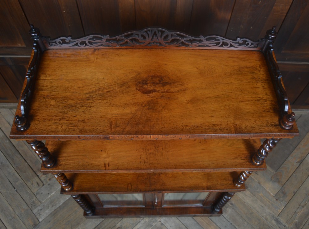 A Victorian rosewood whatnot featuring two open upper shelves supported by barley twist columns, topped with a fretwork gallery, above a lower two-door mirrored cabinet. View II
