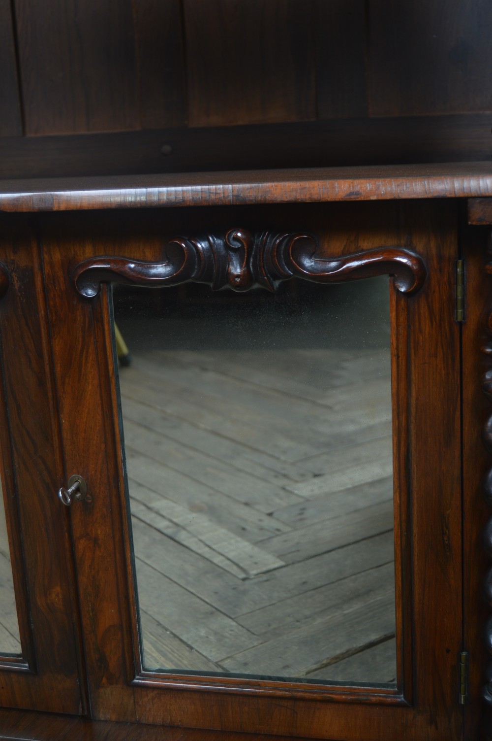 A Victorian rosewood whatnot featuring two open upper shelves supported by barley twist columns, topped with a fretwork gallery, above a lower two-door mirrored cabinet. View XII