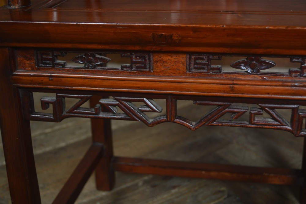 A Chinese carved wooden armchair featuring a continuous curved horseshoe backrail, carved central splat with a figurative relief, and a dark warm brown lacquered finish. View VII