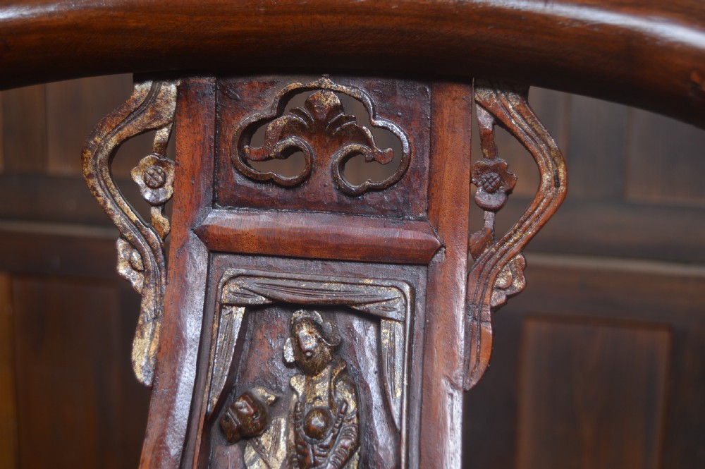 A Chinese horseshoe back armchair made from warm brown lacquered wood, featuring a curved upper crest rail and a central carved splat. View III