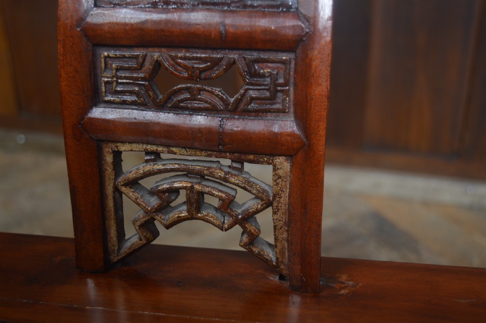 A Chinese horseshoe back armchair made from warm brown lacquered wood, featuring a curved upper crest rail and a central carved splat. View IV