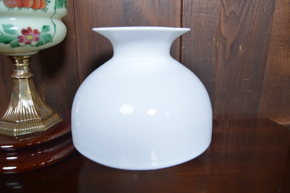 An antique Victorian paraffin oil lamp featuring a hand-painted floral glass reservoir, a brass fluted stem, a white opaline shade, and a circular wooden plinth base. View IX