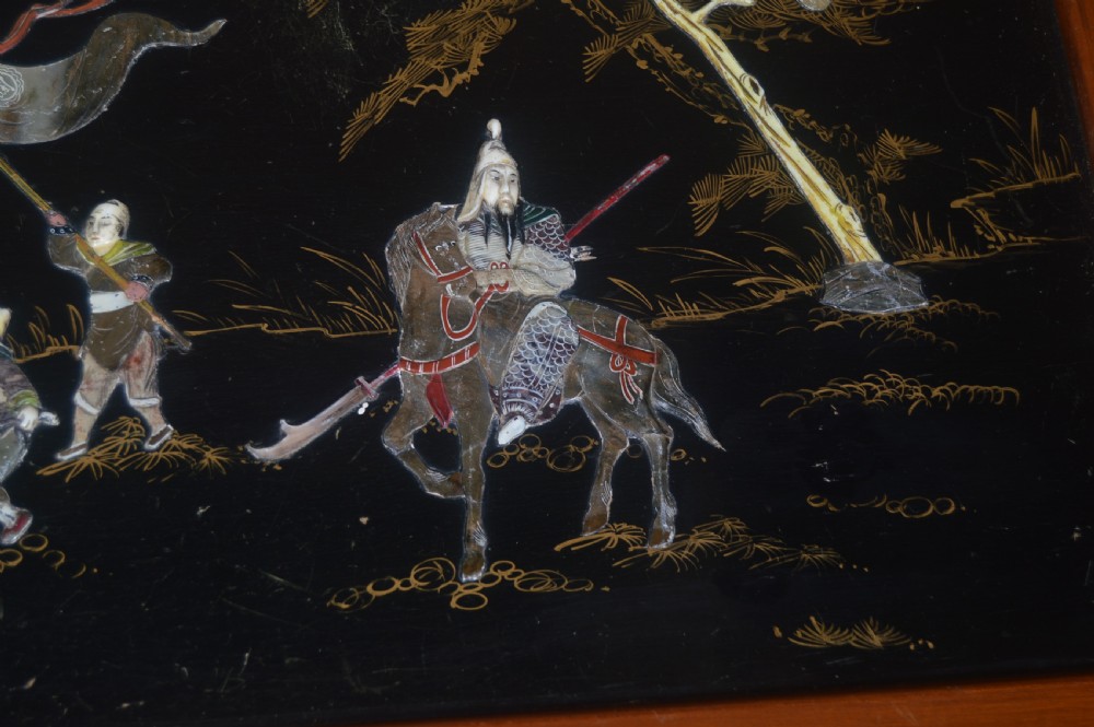 A Chinese camphor wood storage chest featuring a reddish-brown frame, black lacquer panels with figurative inlays, and a brass front clasp. View VIII