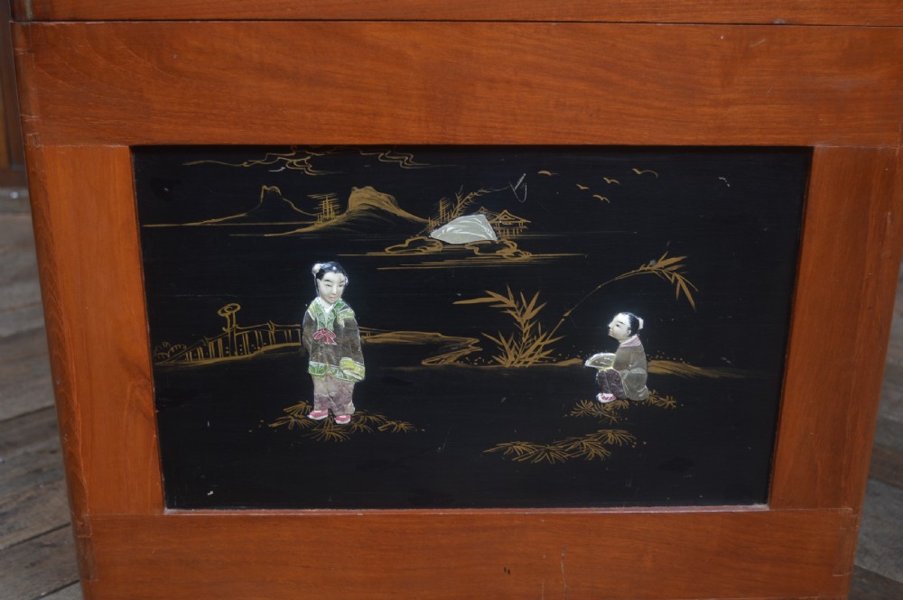 A Chinese camphor wood storage chest featuring a reddish-brown frame, black lacquer panels with figurative inlays, and a brass front clasp. View XI