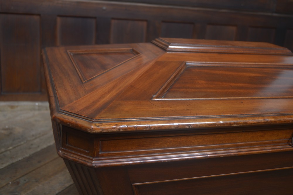 A mahogany sarcophagus-shaped cellarette featuring a tapered wooden body, stepped hinged lid, and carved paw feet. View IV