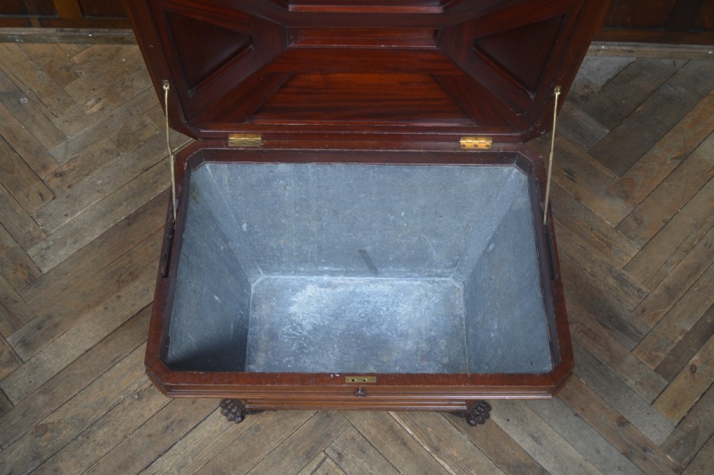 A mahogany sarcophagus-shaped cellarette featuring a tapered wooden body, stepped hinged lid, and carved paw feet. View VI
