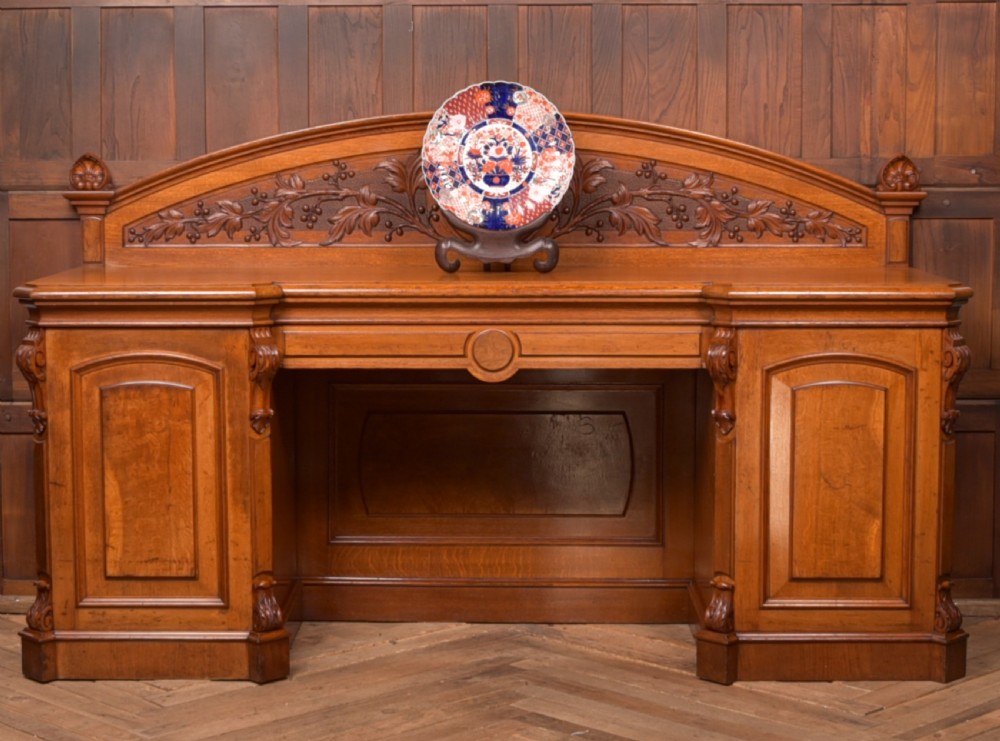 A Victorian oak pedestal sideboard featuring an arched carved backboard with foliage details, twin cupboard pedestals, and a recessed central section. View II