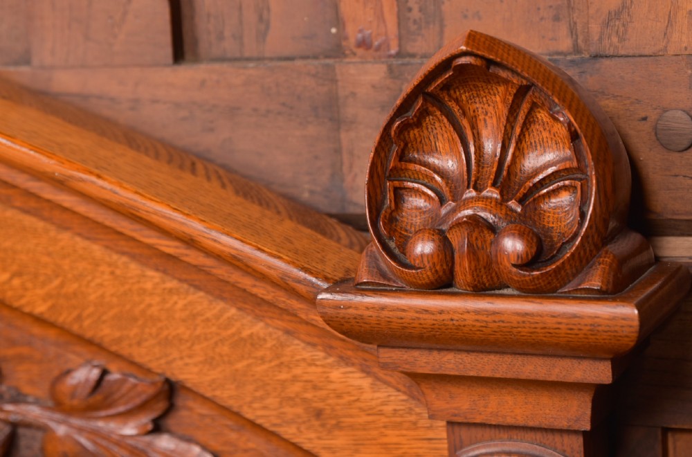 A Victorian oak pedestal sideboard featuring an arched carved backboard with foliage details, twin cupboard pedestals, and a recessed central section. View III