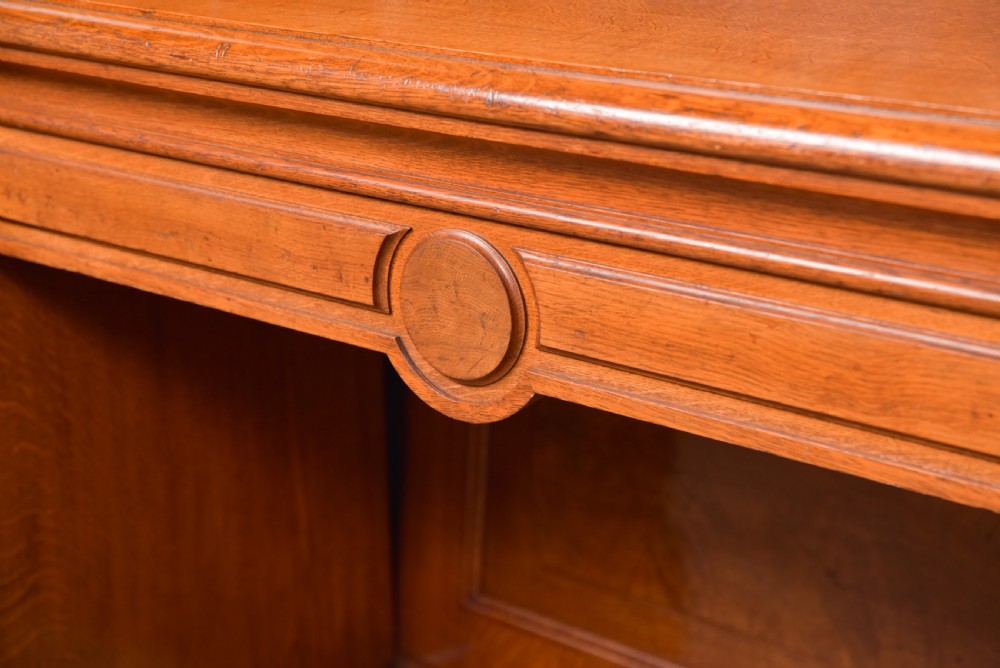 A Victorian oak pedestal sideboard featuring an arched carved backboard with foliage details, twin cupboard pedestals, and a recessed central section. View VI