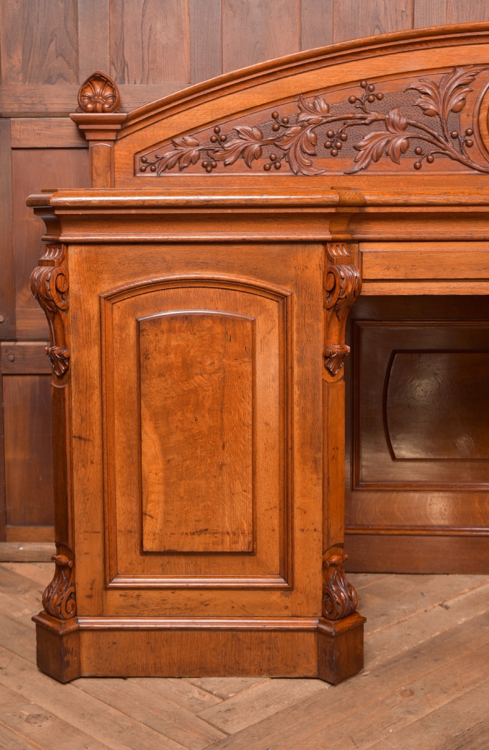 A Victorian oak pedestal sideboard featuring an arched carved backboard with foliage details, twin cupboard pedestals, and a recessed central section. View IX