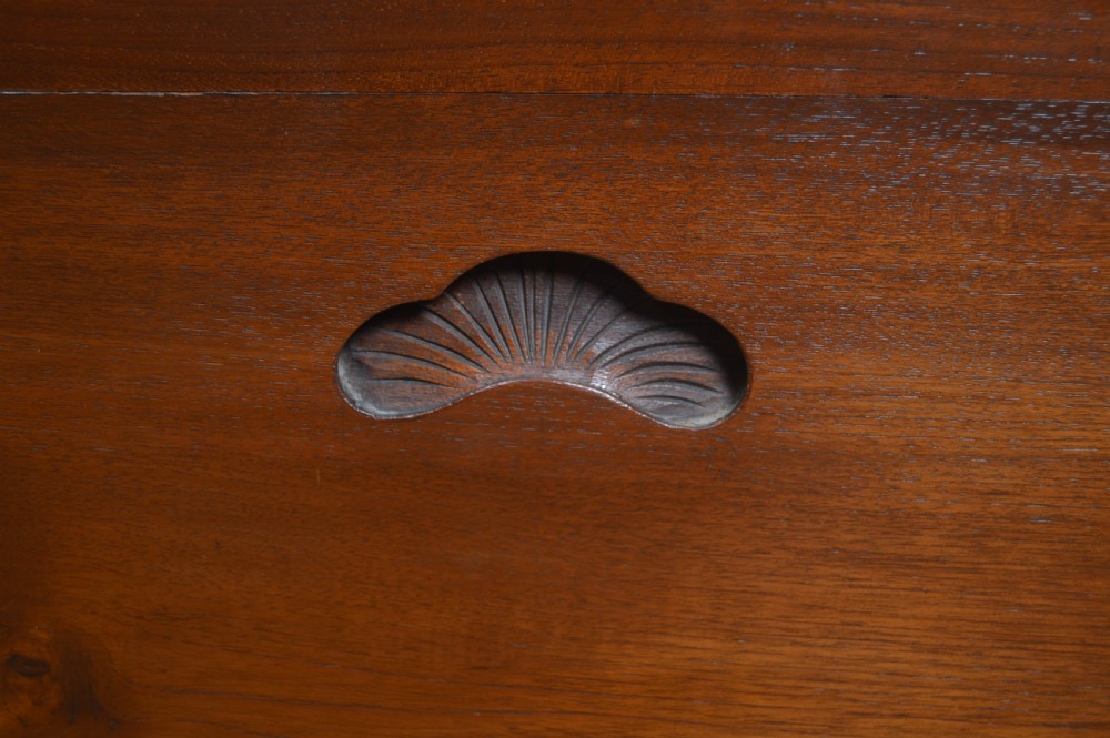 A carved warm brown camphor wood chest featuring a relief dragon motif on the front panel and a decorative circular brass clasp. View XIV
