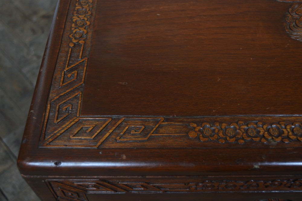 A carved warm brown camphor wood chest featuring a relief dragon motif on the front panel and a decorative circular brass clasp. View XXIV
