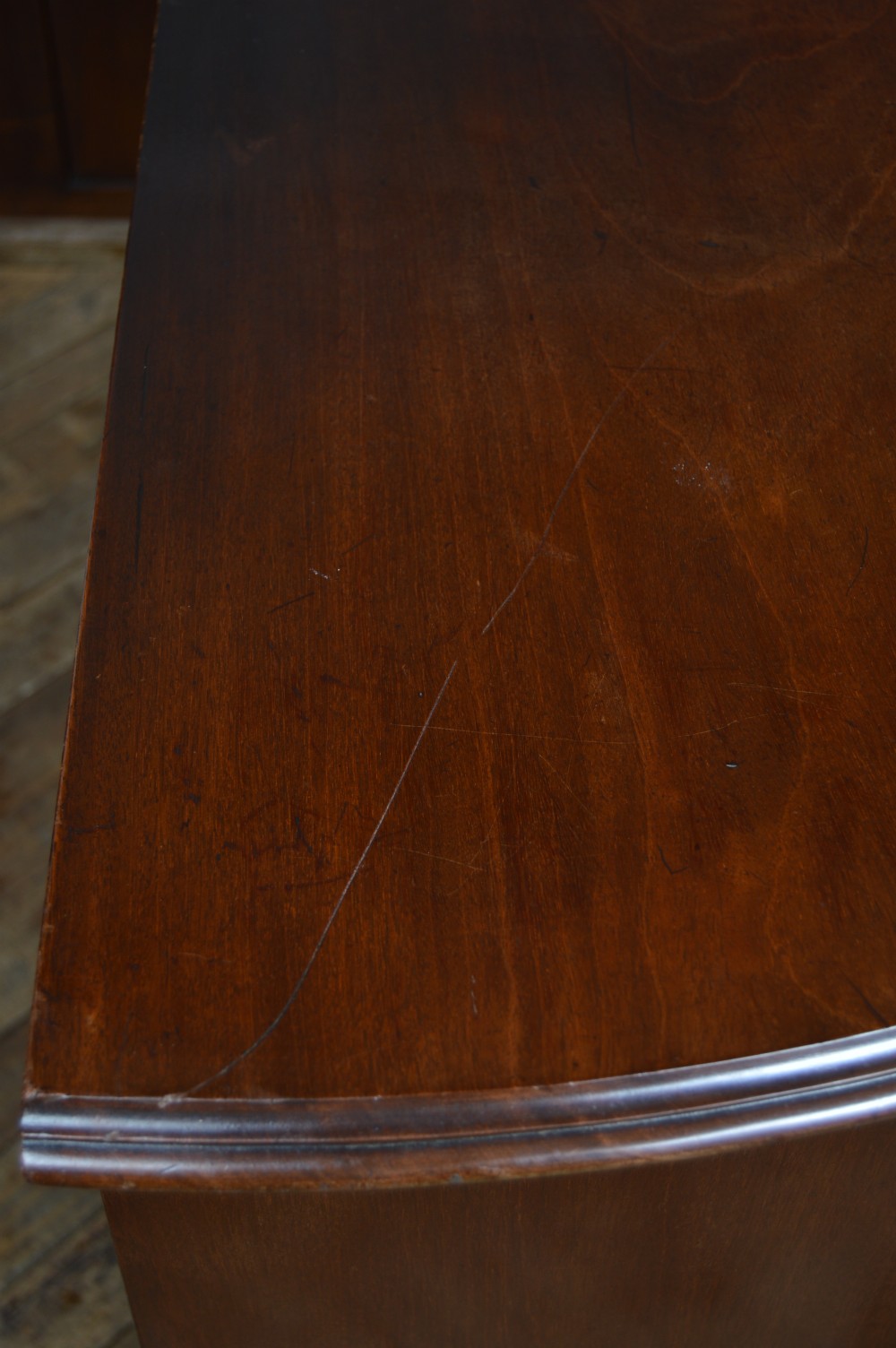 An 18th-century Georgian flame mahogany serpentine chest of drawers featuring four graduated drawers with rococo brass handles and ogee bracket feet. View XV