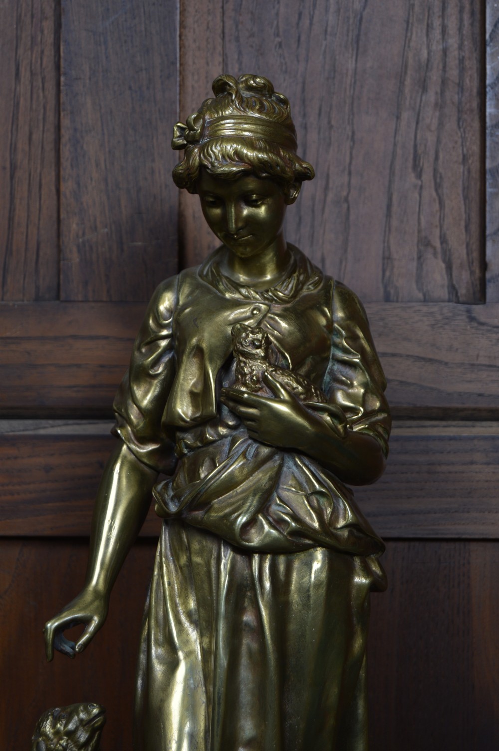 A 19th-century French bronze sculpture depicting a young shepherdess holding a bird beside a lamb on a circular base. View V