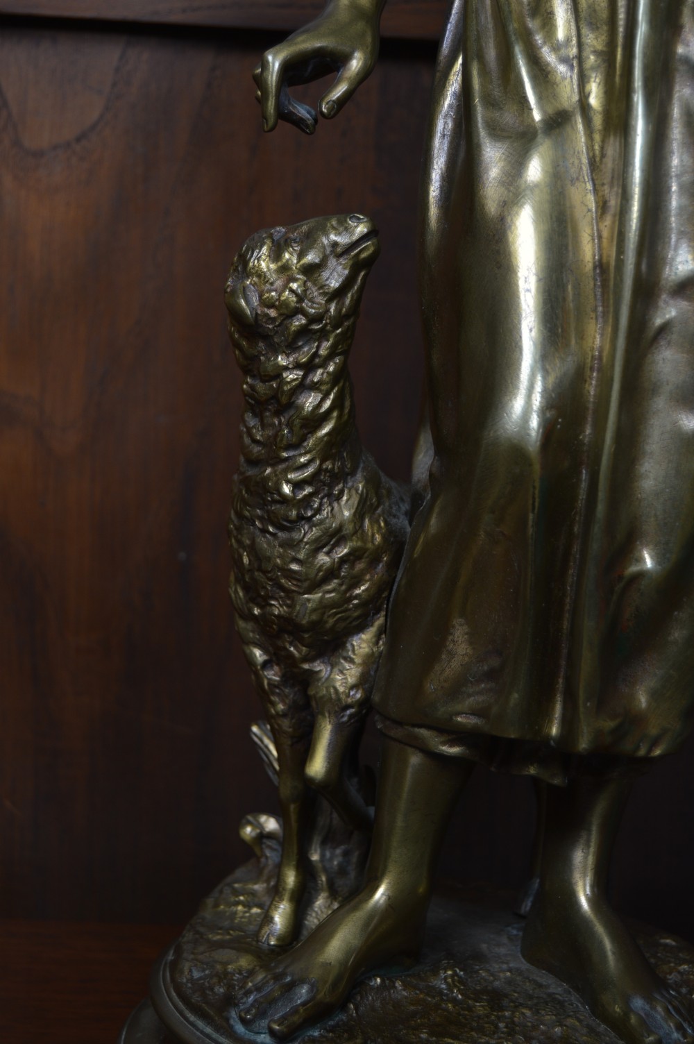A 19th-century French bronze sculpture depicting a young shepherdess holding a bird beside a lamb on a circular base. View VI