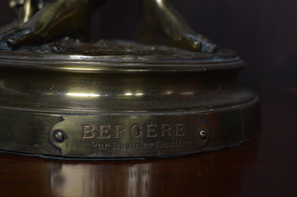 A 19th-century French bronze sculpture depicting a young shepherdess holding a bird beside a lamb on a circular base. View VII