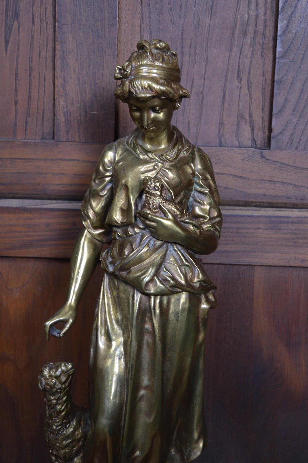 A 19th-century French bronze sculpture depicting a young shepherdess holding a bird beside a lamb on a circular base. View IX