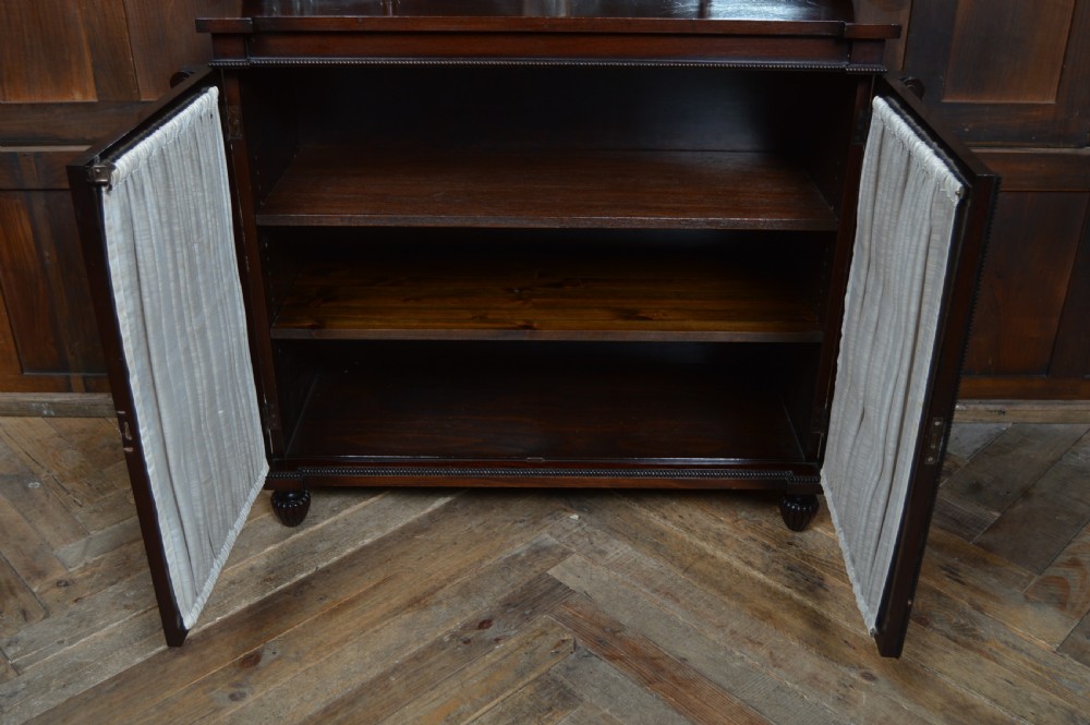 An antique dark mahogany chiffonier featuring a mirrored back shelf with a brass gallery, curved scroll supports, and lower cupboard doors with wire mesh and pleated fabric panels. View XIV