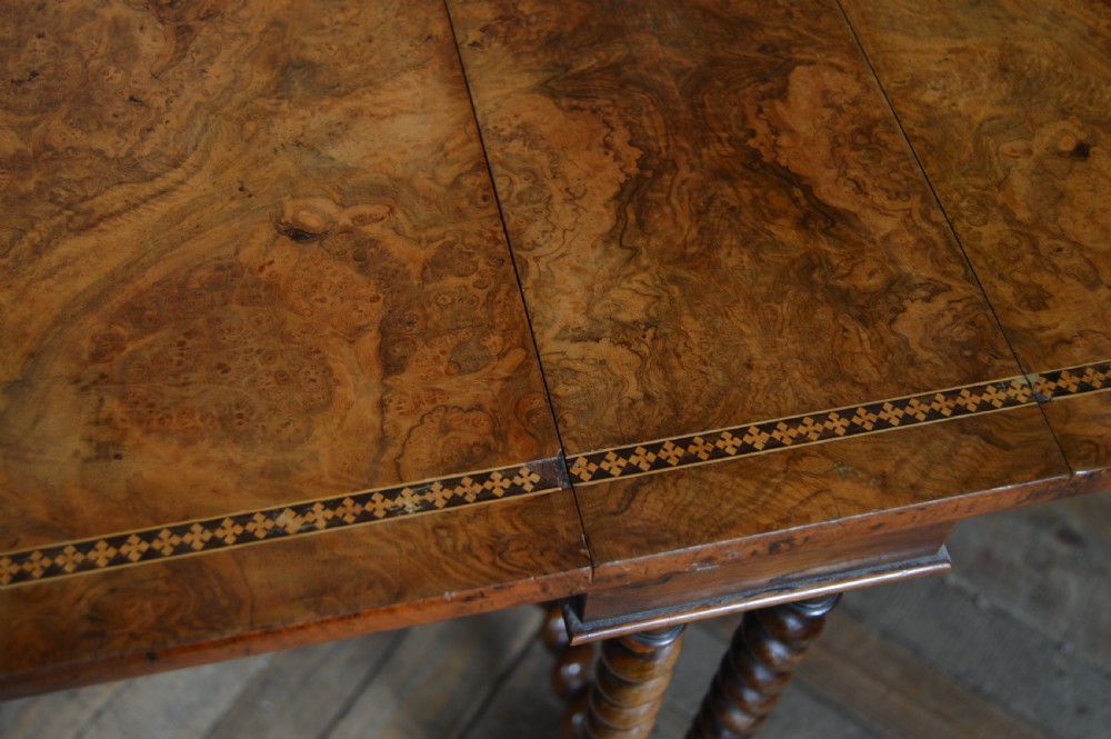 A Victorian burr walnut Sutherland drop-leaf table featuring inlaid geometric borders and barley twist legs on brass castors. View XIII