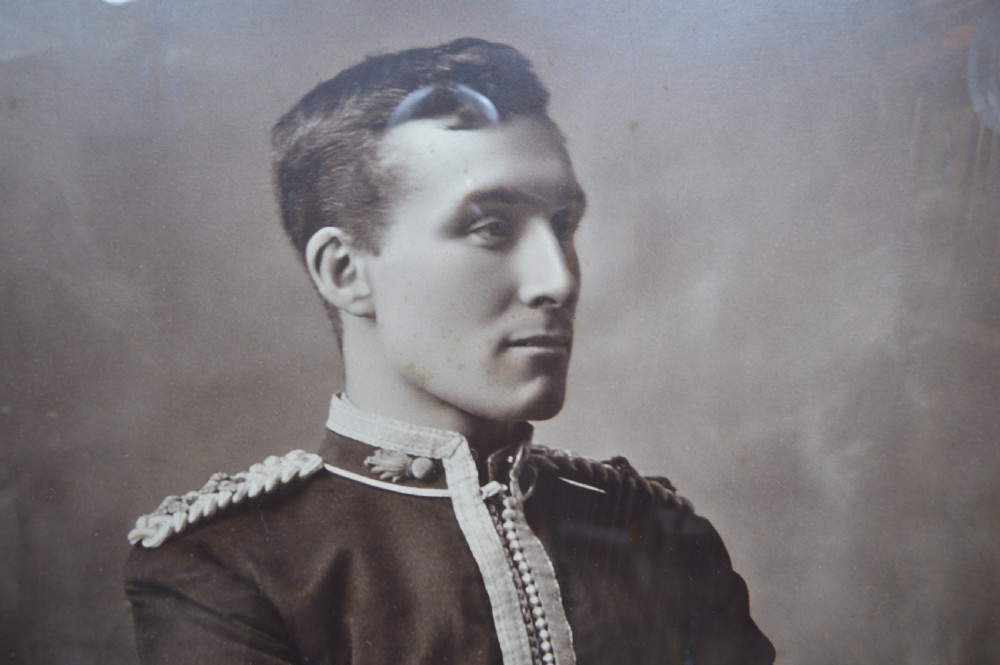 A monochrome photographic portrait of a male military officer in uniform, displayed within a cream mount, gilt slip, and dark moulded oak frame. View V