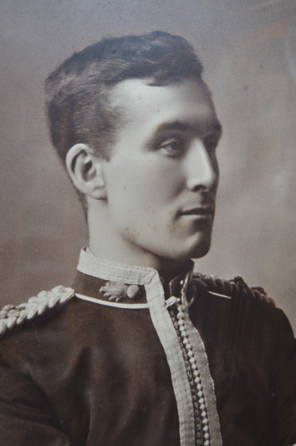 A monochrome photographic portrait of a male military officer in uniform, displayed within a cream mount, gilt slip, and dark moulded oak frame. View VIII