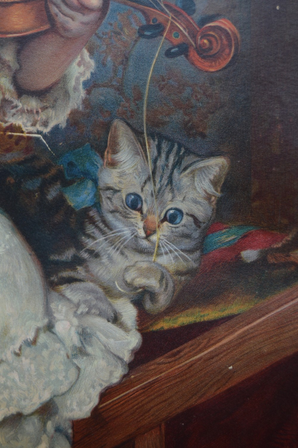 A framed Victorian chromolithograph after Charles Burton Barber depicting a young girl playing a violin to a terrier and kitten, set within a carved dark wood frame. View VIII