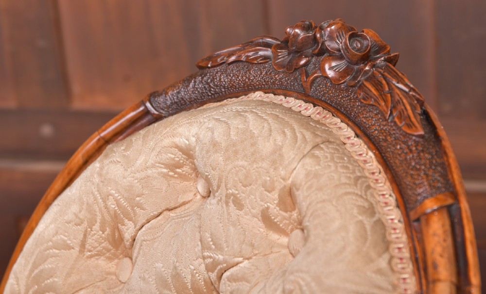 A Victorian carved walnut nursing chair with a button-tufted oval backrest, champagne fabric upholstery, carved cabriole legs, and ceramic castors. View IV