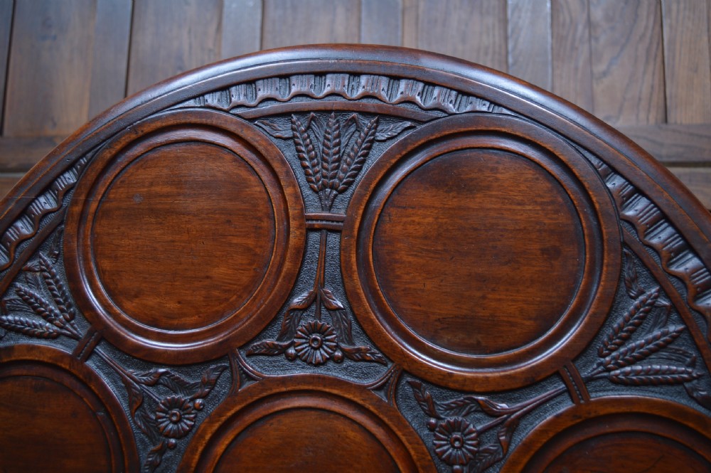 A dark mahogany circular Georgian snap-top supper table featuring carved dished plate recesses, a turned central column, and tripod cabriole legs. View V
