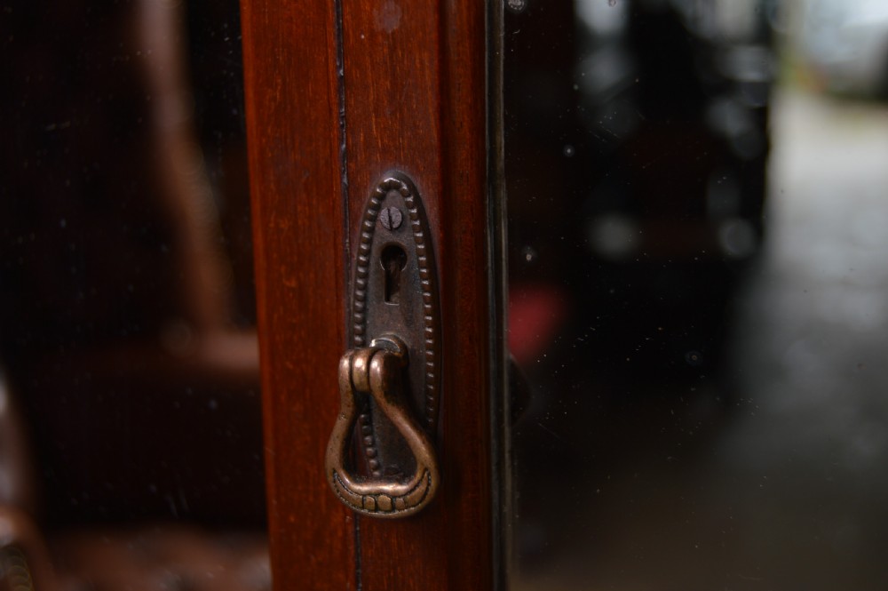 An Edwardian miniature mahogany wardrobe featuring mirrored twin doors, three lower drawers with brass drop handles, and an arched crest inscribed with initials. View X