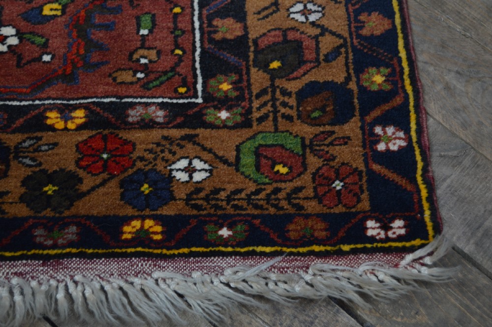A long hand-knotted Turkish rug runner featuring a central light grey and blue geometric medallion on a terracotta red field, framed by dark navy spandrels and a multi-band decorative border. View VI