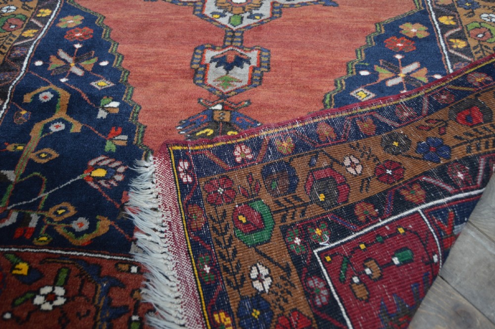 A long hand-knotted Turkish rug runner featuring a central light grey and blue geometric medallion on a terracotta red field, framed by dark navy spandrels and a multi-band decorative border. View IX