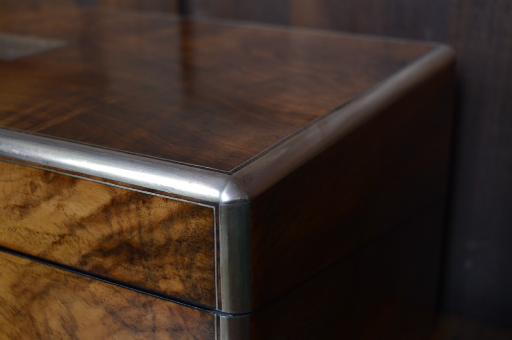 A closed rectangular Victorian burr walnut writing slope featuring metal border trim, a keyhole escutcheon, and an engraved metal presentation plaque on top. View IV