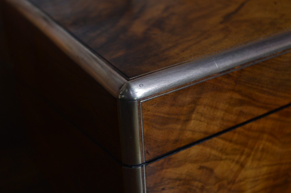 A closed rectangular Victorian burr walnut writing slope featuring metal border trim, a keyhole escutcheon, and an engraved metal presentation plaque on top. View V