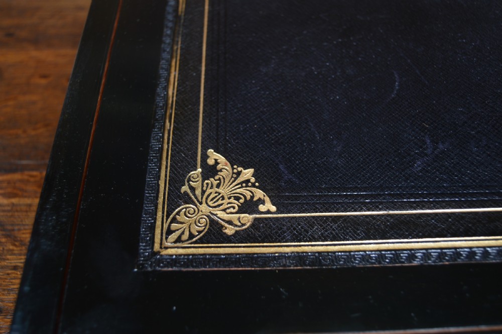 A closed rectangular Victorian burr walnut writing slope featuring metal border trim, a keyhole escutcheon, and an engraved metal presentation plaque on top. View IX