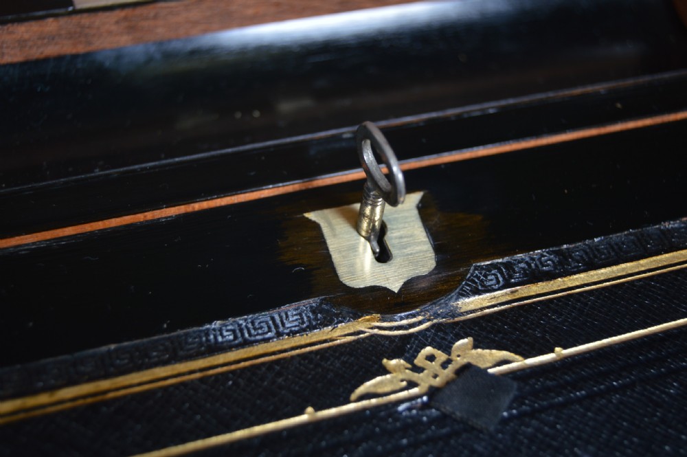 A closed rectangular Victorian burr walnut writing slope featuring metal border trim, a keyhole escutcheon, and an engraved metal presentation plaque on top. View X