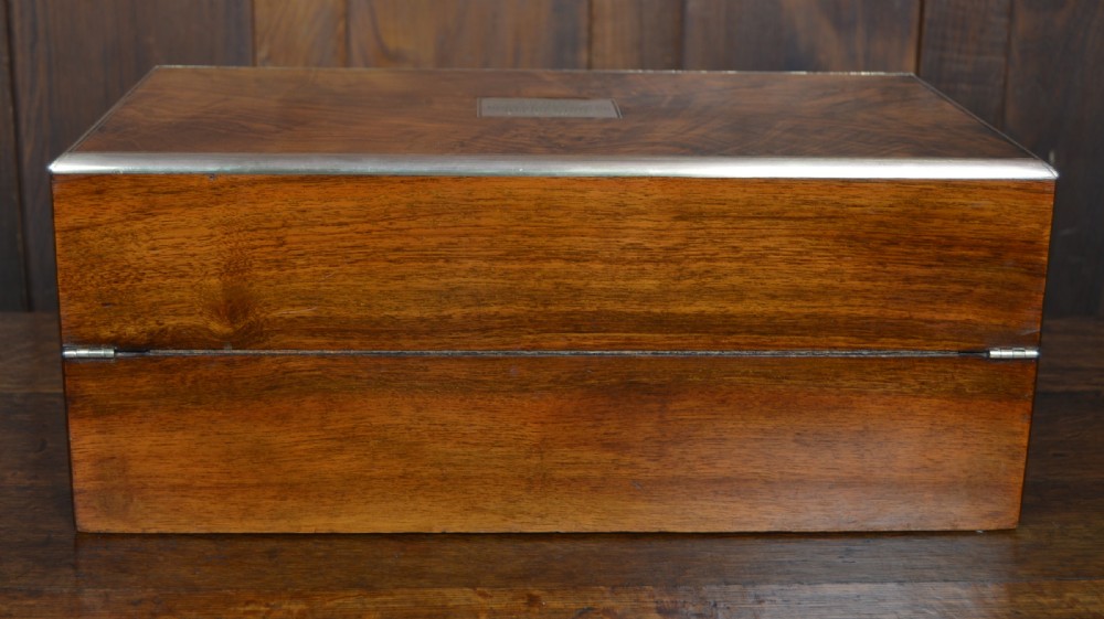 A closed rectangular Victorian burr walnut writing slope featuring metal border trim, a keyhole escutcheon, and an engraved metal presentation plaque on top. View XXII