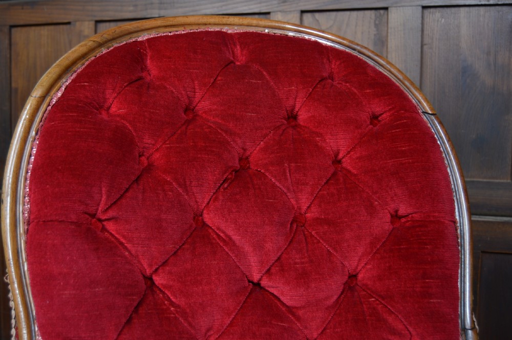 A Victorian walnut parlour armchair with crimson red velvet button-backed upholstery, carved cabriole front legs, and brass castors. View IX