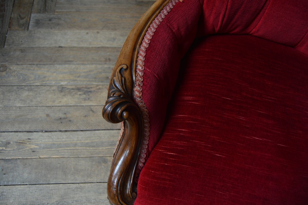 A Victorian walnut parlour armchair with crimson red velvet button-backed upholstery, carved cabriole front legs, and brass castors. View XI