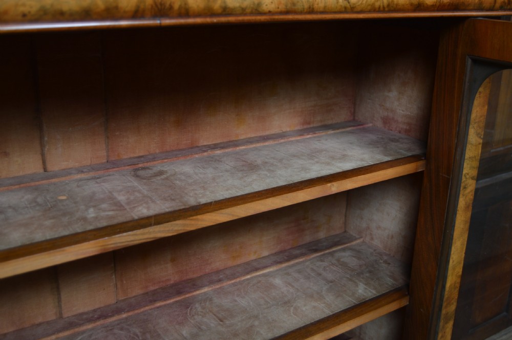 A Victorian burr walnut glazed bookcase featuring two rounded arch glass doors, adjustable interior shelves, and a moulded cornice. View VIII
