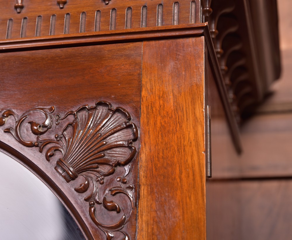 An Edwardian mahogany glazed bookcase featuring geometric astragal glazing, carved corner spandrels, and bottom drawers with drop handles. View VIII