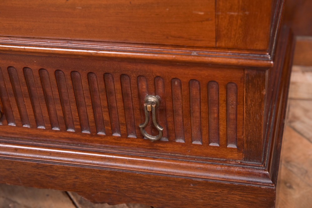 An Edwardian mahogany glazed bookcase featuring geometric astragal glazing, carved corner spandrels, and bottom drawers with drop handles. View IX