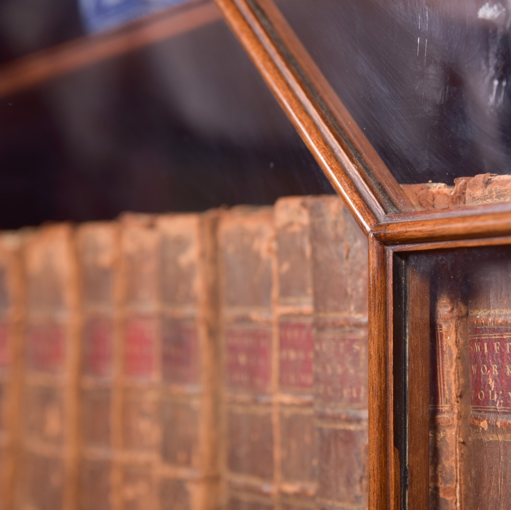 An Edwardian mahogany glazed bookcase featuring geometric astragal glazing, carved corner spandrels, and bottom drawers with drop handles. View XXV