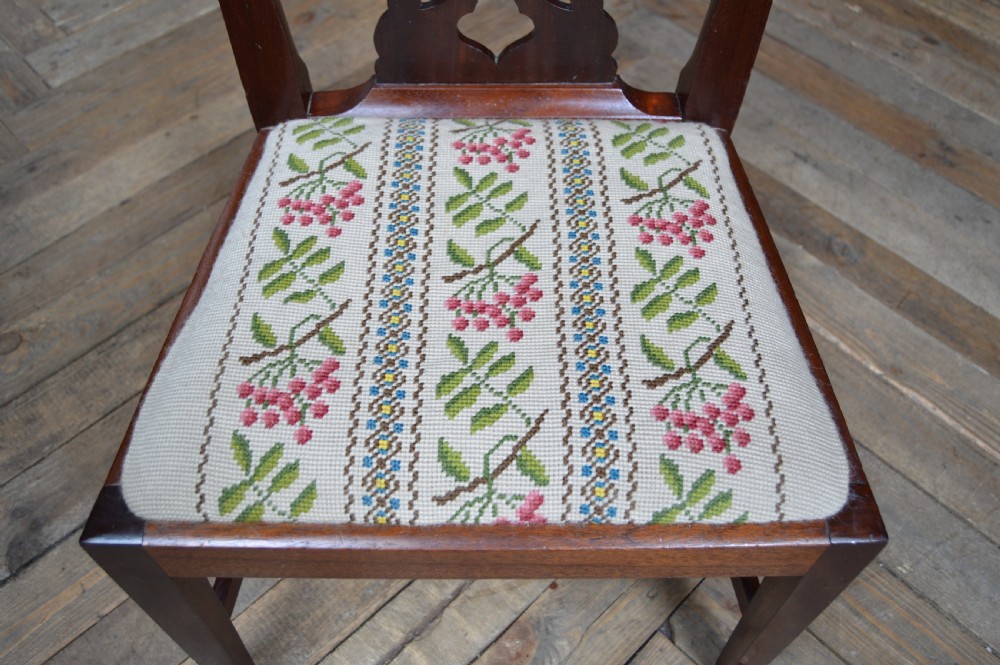 A Chippendale style mahogany gossip chair featuring an intricate pierced back splat, straight square legs, and a floral needlepoint seat. View IV