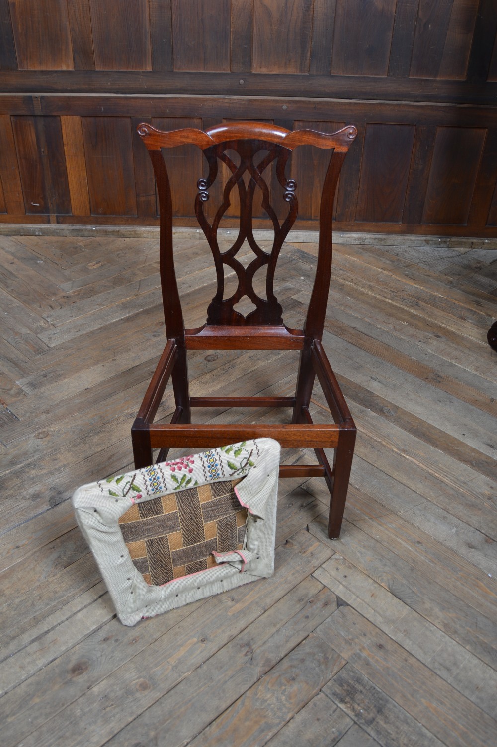 A Chippendale style mahogany gossip chair featuring an intricate pierced back splat, straight square legs, and a floral needlepoint seat. View V