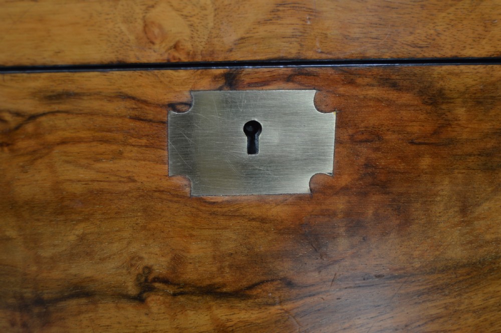 A closed Victorian burr walnut writing slope featuring brass corner straps, stringing inlay, and a brass keyhole escutcheon. View IV