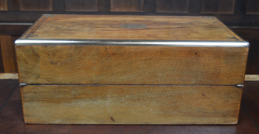 A closed Victorian burr walnut writing slope featuring brass corner straps, stringing inlay, and a brass keyhole escutcheon. View XV