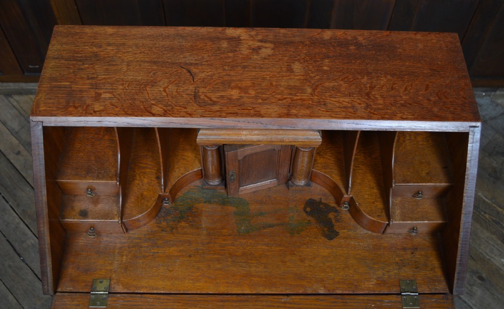 An Edwardian oak slant-front bureau on stand featuring brass drop handles, a shaped lower apron, and four cabriole legs ending in pad feet. View VIII