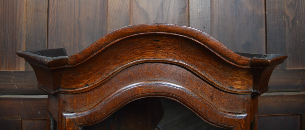 A dark oak tabletop display cabinet featuring an arched pediment, glazed front door with a brass teardrop handle, and glazed side panels. View V